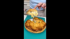 a person is cutting into a pie on a blue tray with a piece missing from it