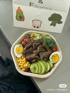 a plastic container filled with meat and veggies next to a box of eggs