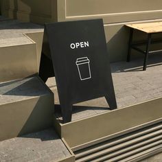 an open sign sitting on the side of some steps next to a table and bench