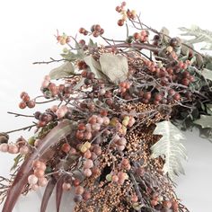 an arrangement of berries and leaves on a white surface