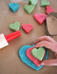 someone is decorating heart shaped cookies with icing