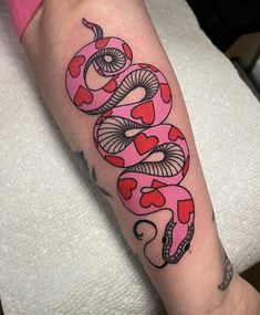 a woman's arm with a pink and black snake tattoo on the left forearm