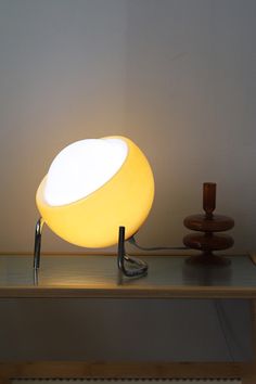 a yellow lamp sitting on top of a wooden table next to a brown object with a white light