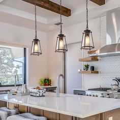 a kitchen with two pendant lights hanging from the ceiling and an island in front of it