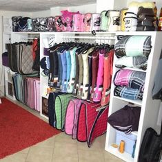 a room filled with lots of colorful bags and handbags on shelves next to a red rug