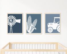 three blue and white pictures hang on the wall above a crib