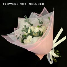 a bouquet of white flowers is wrapped in pink paper and tied to a black background