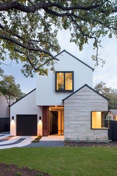 a modern house with white brick and black shutters on the front, surrounded by green grass