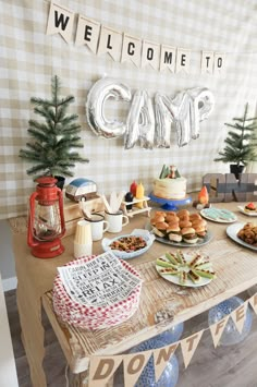 a table topped with cakes and desserts next to a welcome sign that says camp