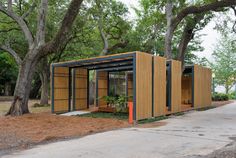 a small wooden structure sitting on the side of a road next to a tree filled park