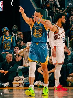 two basketball players are on the court and one has his hand up in the air