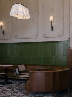 a room with green paneling and two round tables in front of the wall that has lights hanging from it