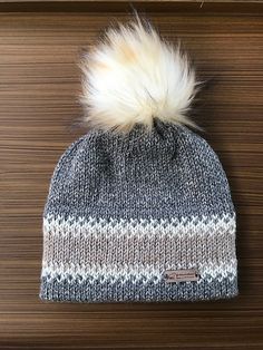 a knitted hat with a white and grey pom - pom on top