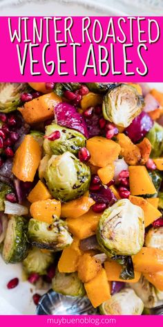 a white plate topped with brussel sprouts, squash and pomegranate