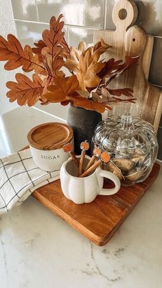 a wooden tray topped with two mugs filled with coffee and cinnamon sticks on top of a counter