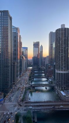 an aerial view of a city with tall buildings and river in the foreground at sunset