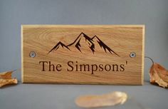 a wooden sign that says the simpsonss with mountains in the background and leaves on the ground