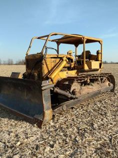 an old bulldozer sitting in the middle of a field with it's front end missing