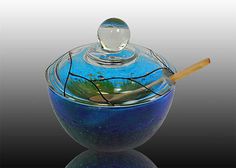 a blue glass bowl with a wooden stick sticking out of it's top and bottom