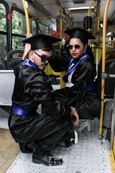 two people in graduation robes sitting on a bus