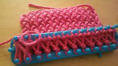 a pink and blue crocheted object sitting on top of a wooden table next to a pair of scissors