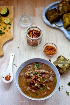 a bowl of soup on a table with pickles and other food items around it