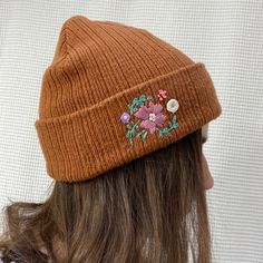 a woman wearing a brown hat with flowers on the side and buttons at the top