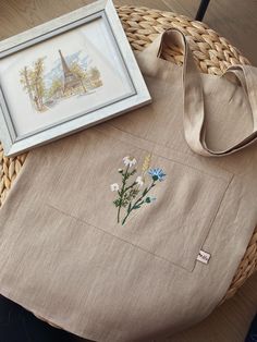 a bag with flowers on it sitting next to a picture frame and framed artwork in a basket