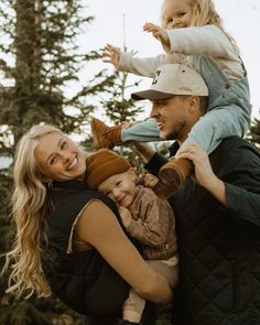 a man, woman and child are posing for a photo in front of some trees