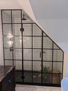 an attic bathroom with black and white tile on the walls, shower stall, sink and toilet