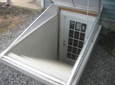 an open door on the side of a house with gravel around it and a metal roof