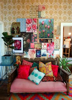 a living room filled with lots of colorful pillows and pictures on the wall above it