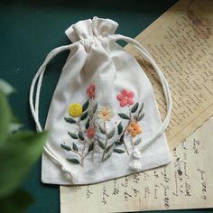 a drawstring bag with flowers on it sitting next to an old handwritten letter