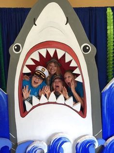 some people are posing for a picture in a shark shaped photo booth at a theme park