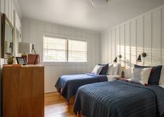 two beds in a room with wooden floors and white walls