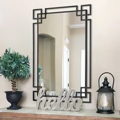 a mirror sitting on top of a dresser next to a potted plant and lamp