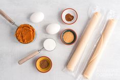 an assortment of ingredients for making bread on a white surface with rolling pin, eggs and cinnamon sticks