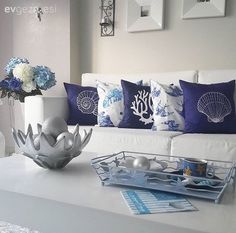 a living room filled with white furniture and blue pillows