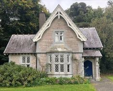 an old stone house with a blue door and window panes in the front yard