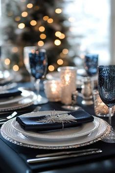 the table is set with black and white plates, silverware, and candlesticks