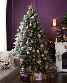 a decorated christmas tree in a living room with purple walls and white trimmings