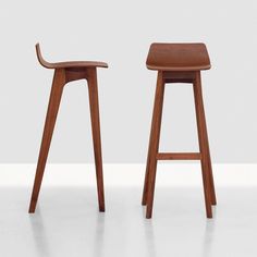 two wooden stools sitting next to each other on a white floor in front of a wall