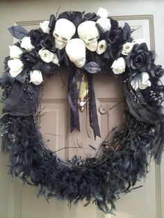 a wreath decorated with black feathers and white flowers is hanging on the front door,