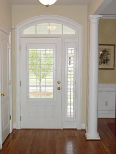 an empty entryway with wooden floors and white columns on either side of the door