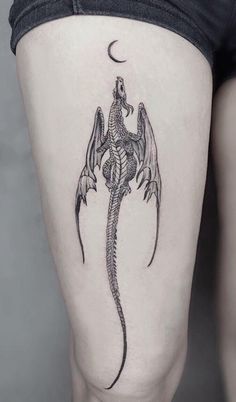 a woman's thigh with a dragon tattoo on the lower part of her leg