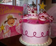 there is a pink cake with cupcakes and tiara on it next to a book