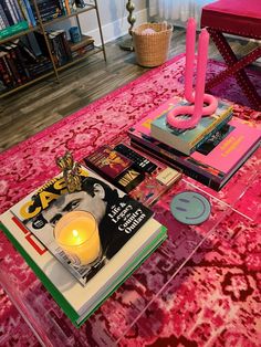 a table topped with books and candles on top of a pink rug