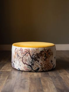 a white and yellow ottoman sitting on top of a wooden floor next to a wall