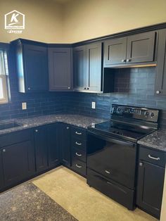 an empty kitchen with black cabinets and granite counter tops