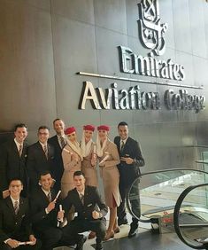 a group of men and women posing in front of the emirates aviation club entrance sign